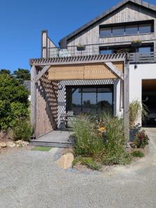 a house with a wooden garage with a balcony at Appartement bord de mer in Lampaul-Plouarzel