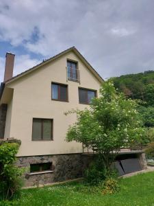 a house with a stone wall and a tree at Apartmán Lesný Dvor in Martinske Hole