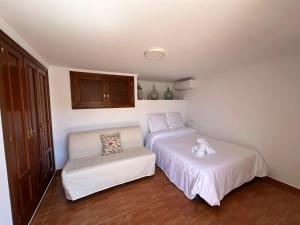 a bedroom with two beds and a chair at Casa Rural Villa María 2061 in Torrox