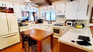 a kitchen with white cabinets and a wooden table in it at Pine Hills Cabin in Julian in Julian +14 photos