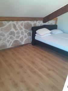 a room with two beds and a stone wall at Apartman 4 sa spavacom in Zelenika