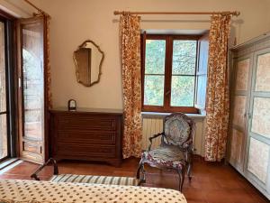 a room with a chair and a dresser and windows at La Casetta di Serenella in Andali
