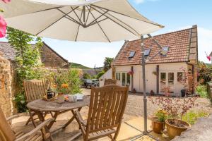a table and chairs with an umbrella in front of a house at 2 Bed in Bridport oc-dc111 in Chideock