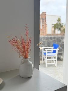 a white vase sitting on a counter with flowers in it at Giasemi Fira Studios in Fira