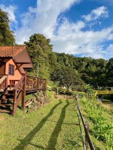 a house in a field with a fence at Chales Fazenda Cantinho do Selado in Monte Verde