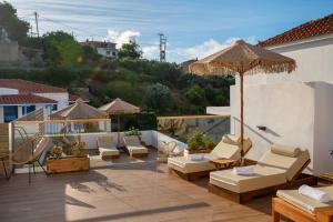 a patio with chairs and umbrellas on a roof at Galini Hellenic Hospitality in Patitiri