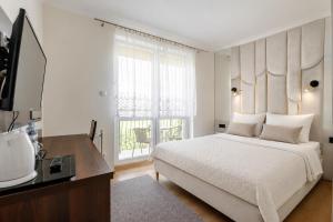 a white bedroom with a large bed and a window at RAMZES USTKA -pokoje z balkonami, parking gratis ,rowery ,dobry dojazd do plazy i centrum in Ustka