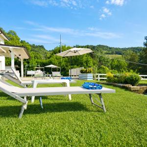 a white picnic table and an umbrella in the grass at TerrazzaPonente in Monte San Pietro