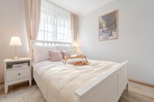 a white bedroom with a bed with a tray on it at Apartament Prowansalski in Nałęczów