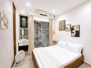 a white bedroom with a bed and a bathroom at Lacasa Homestay in Hue