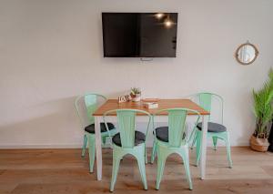 a dining room table with green chairs and a television at MOOKI Sky by Lake in Villach