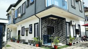 a white and black building with potted plants in front of it at JRC Chariot Luxury Apartment in Omole