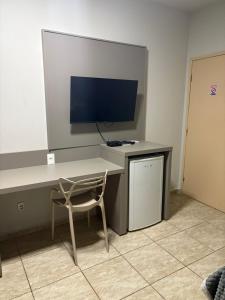 a desk with a monitor and a chair in a room at Quefren Residence Hotel in Uberaba