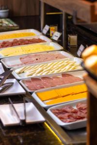 a buffet with many different meats and cheeses on plates at Cataratas Park Hotel e Eventos in Foz do Iguaçu +97 photos
