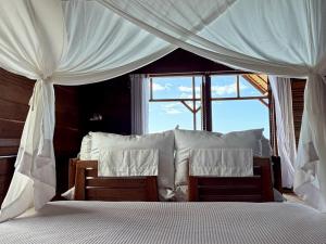 a bedroom with a bed with white curtains and a window at ipyum Premium Overwater Guest House in Pulau Birie