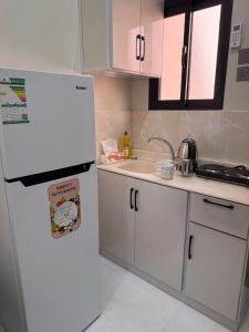 a kitchen with a white refrigerator and a sink at Hail View شقق فيو حائل المخدومة in Hail +11 photos