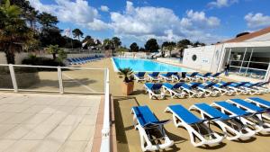 a swimming pool with blue lounge chairs in front of a resort at Mobil-home bww camping le bois dormant in Saint-Jean-de-Monts