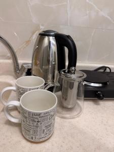 a tea kettle and two coffee cups on a counter at Hail View شقق فيو حائل المخدومة in Hail