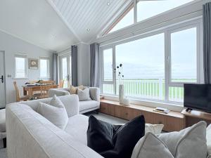 a living room with white furniture and large windows at Sea View Retreat Lodge in Heysham