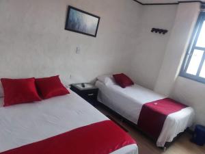 two beds in a room with red and white at Hotel Los Balcones in San Agustín