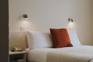 a bed with white sheets and an orange pillow on it at Hydro Hotel in Lisdoonvarna