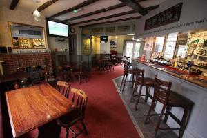 a restaurant with a bar with wooden tables and chairs at The Old Bear Inn in Cricklade