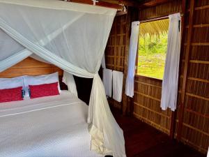 a bedroom with a canopy bed with a window at ipyum Premium Beach Guest House in Sageurin