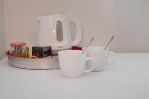 three white cups sitting on a counter with a toaster at Penzion Sv. Duch in Český Krumlov