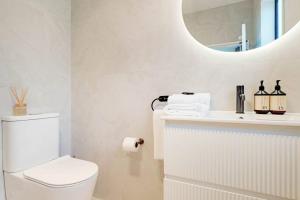a white bathroom with a toilet and a mirror at Cosy Pukekohe Self-Contained Unit with Kitchenette in Pukekohe East +12 photos