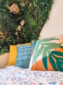 a bed with pillows in front of a wall with plants at Studio Valentigney in Valentigney