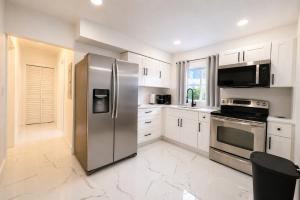 a kitchen with stainless steel appliances and white cabinets at 05 Modern Co-Living Home with Newly Renovated Private Rooms Available in Miami