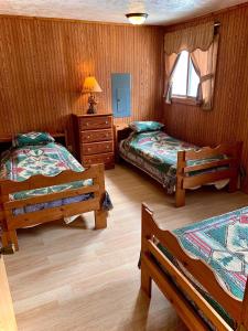 a bedroom with two beds and a dresser and a window at Benzonia Rustic Resort in Benzonia