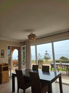 a dining room with a table and chairs and a large window at Villa sur la plage in Tiznit