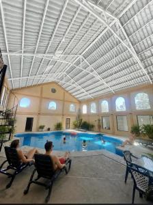two people sitting in chairs by a swimming pool at Hotel Mansion Tarahumara in Areponapuchi