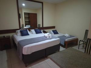 a hotel room with two beds and a mirror at Palace Hotel Jacutinga JS in Jacutinga