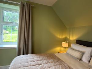 a bedroom with a large bed and a window at Greenkeepers Cottage in Tobermory