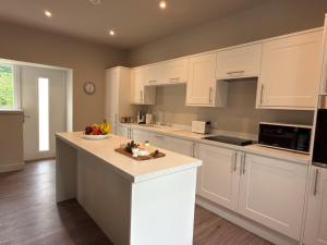a kitchen with white cabinets and a counter top at Greenkeepers Cottage in Tobermory