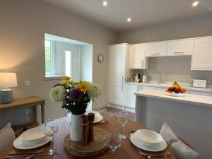 a kitchen with a table with a vase of flowers on it at Greenkeepers Cottage in Tobermory +30 photos