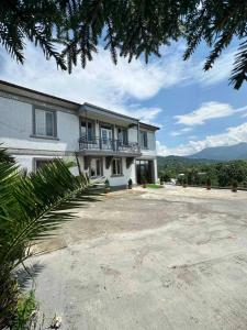 a large white building with a balcony on it at Guest House Ucha in Stantsiya Chakva