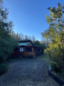 a log cabin with a gravel driveway in front of it at Refugio Lawentu Linares Colbun in Los Rabones
