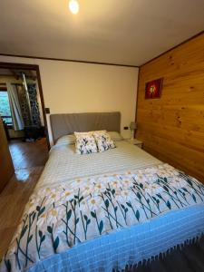 a bedroom with a large bed with a wooden wall at Refugio Lawentu Linares Colbun in Los Rabones