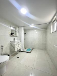 a white bathroom with a sink and a toilet at Guest House Ucha in Stantsiya Chakva +16 photos