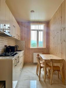 a kitchen with a table and chairs in a room at Guest House Ucha in Stantsiya Chakva