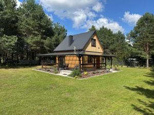 a house with a black roof on a grass field at Dolina Jelenia in Gorczyca