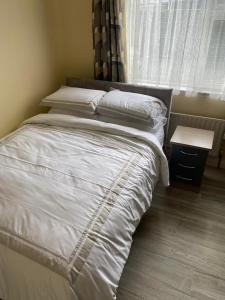 a bedroom with a bed with white sheets and a window at Athenry Stay in Athenry