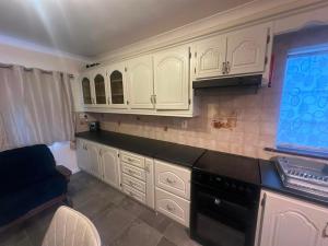 a kitchen with white cabinets and black counter tops at Athenry Stay in Athenry