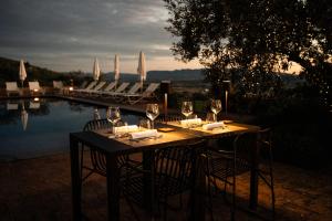 ein Tisch mit Weingläsern und Stühlen neben einem Pool in der Unterkunft La Quercetta in Foligno