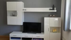 a living room with a tv and white cabinets at Ferienhaus Stricker in Ehrwald