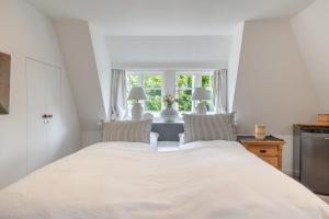 a white bed in a room with a window at Beachday Kampen in Kampen