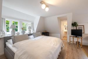a white bedroom with a large bed and a television at Beachday Kampen in Kampen